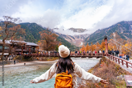 Young solo female traveler enjoying a beautiful autumn day and stunning nature landscape while exploring Kamikochi National Park
