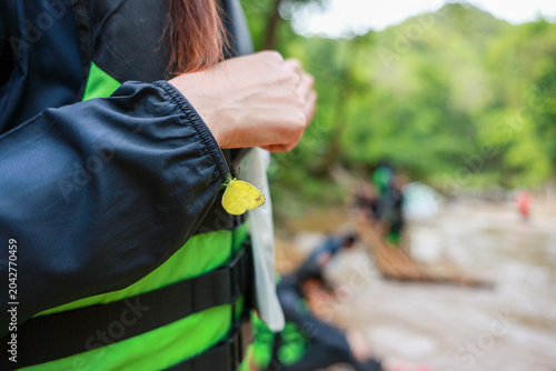 Bild auf Leinwand Woman wearing bright green life jacket holding white cloth by river feeling prep