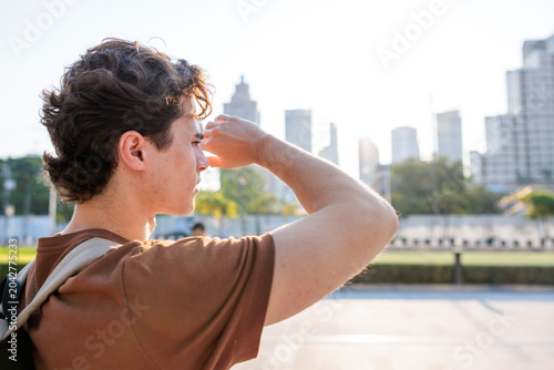 Man shields eyes, gazing at city skyline during urban heatwave