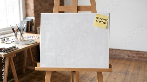 A blank white canvas on a wooden easel features a yellow sticky note reading 'Permission Granted', a powerful metaphor for overcoming creative blocks and authorizing oneself to begin.