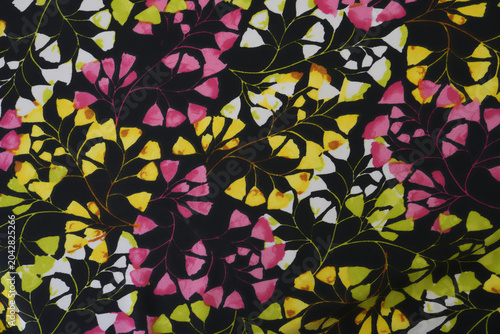 floral leaf pattern printed on black fabric, featuring pink, yellow and lime green petals and delicate veins