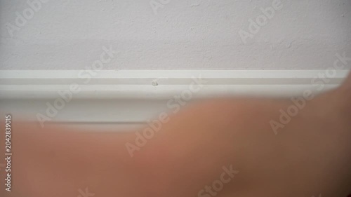 Closeup of a man's hand wiping dirt, hair, and grime off of a white wall using a white towel. Daily tasks. Household chores. Spring cleaning.