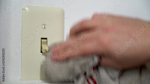 Man cleans an old light switch cover with a white towel. Closeup. Housework and chores. Sanitizing the home and household surfaces. 