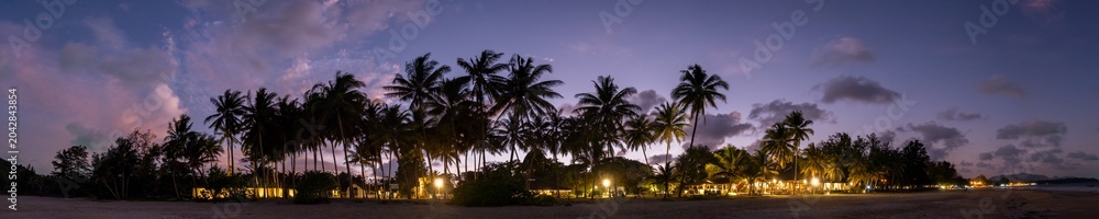 Fototapeta premium Dramatic panorama sky with cloud on twilight time at a beach with coconut palm trees.