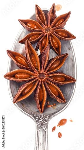 Star anise spices on silver spoon against white background