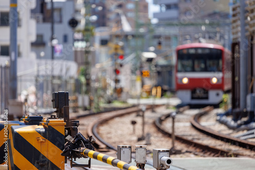 Photos 降りた踏切の遮断機とボケ味のある赤い電車の風景