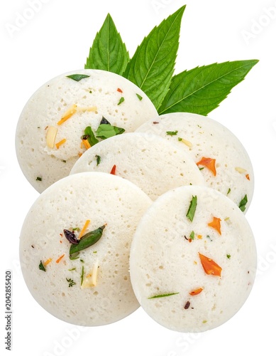 Steamed savory idli a south indian dish with fresh green herbs on a white surface
