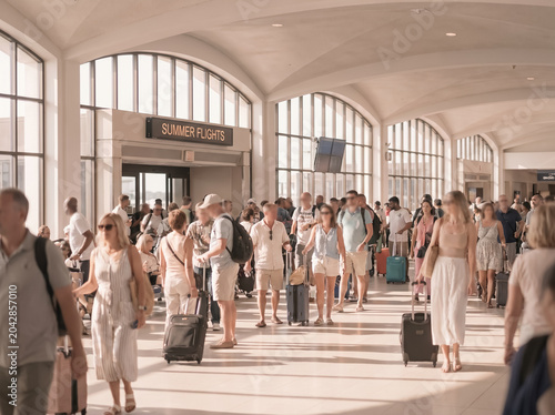 Crowd of passengers walking through a sunny airport hall