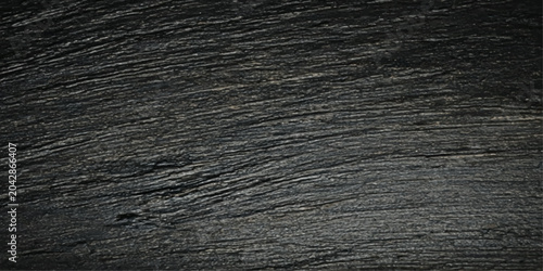Photos A macro shot captures the intricate, textured grain of dark, weathered wood, revealing the natural beauty of its surface with subtle striations and a rustic feel