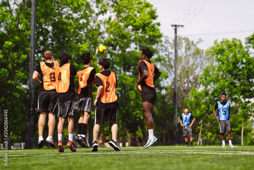 Foto Soccer player jumping to block yellow ball over defense wall on field