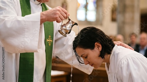 A priest performs a baptism ceremony, pouring water over a person's head.