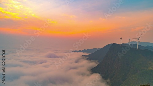 Wind Turbines on Mountain Ridge Above Clouds at Sunset