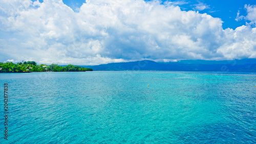 beautiful view of tropical beach with mountain backdrop and clear sky
