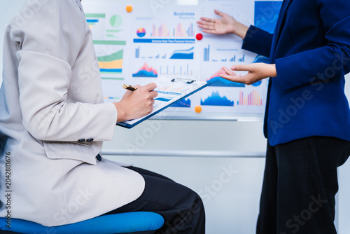 Fotografie Experienced Asian woman trains new employee in office work, teaching secretarial duties, document management, assistant manager responsibilities