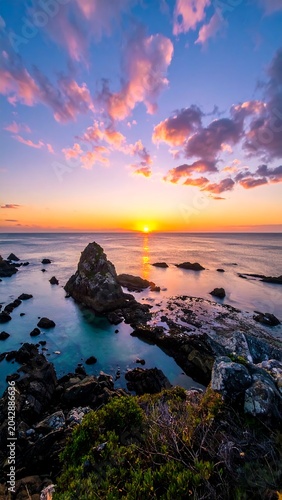 Stunning coastal sunset scene with dramatic sky and rocky shoreline views