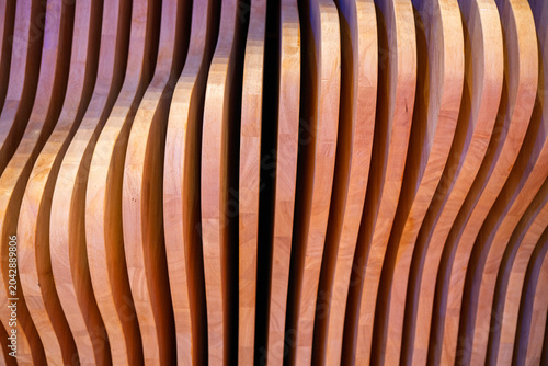 Картината върху платно A full-frame shot of a decorative architectural wall feature consisting of numerous vertical, closely arranged wooden slats with unique curved profiles, creating a rhythmic wave-like pattern