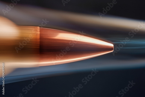 Ultra-realistic close-up of a polished copper bullet tip spinning in the air, reflecting light with a sleek aerodynamic shape against a motion-blurred background