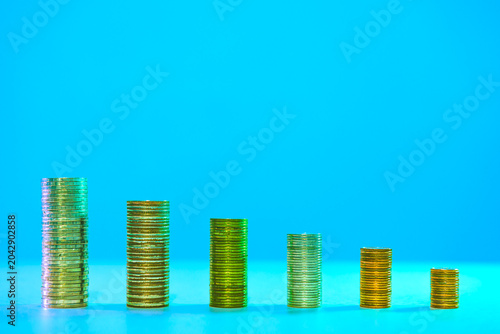 Financial Series : Descending coin stacks symbolize declining income, shrinking wealth, and investment loss in a changing economy.