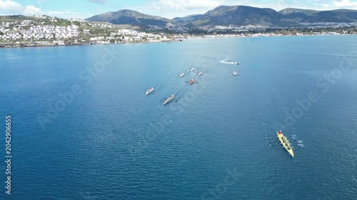 Aerial View of Professional Rowing Teams Competing in a Regatta near Scenic Coastal Town with Mountains. High quality 4k footage