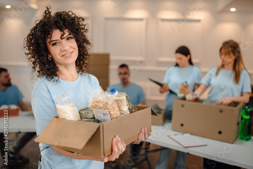 Tableau sur toile Woman volunteer holding donation box with food items