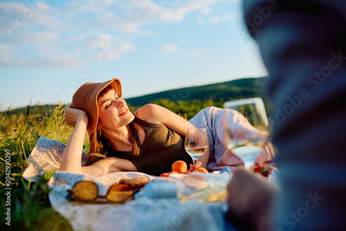Foto Young woman in a hat lying on a blanket, smiling with closed eyes, enjoying a gl