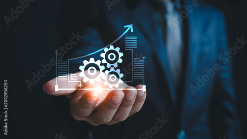 Business process automation concept, businessman holding glowing gears and growth arrow, digital transformation and industrial optimization strategy