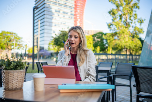 Woman talking on phone working remotely outdoors