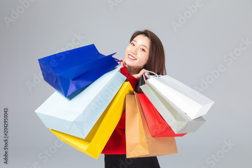 Tableau sur toile Smiling Young Woman Carrying Colorful Shopping Bags