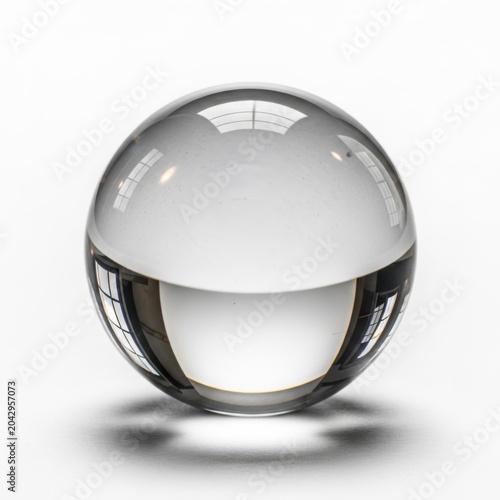Single clear glass sphere reflecting a room interior isolated on a plain white background