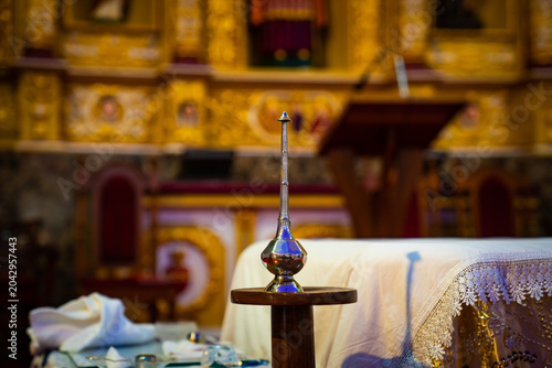 Schilderij op canvas A silver holy water sprinkler, also known as an aspergillum, resting on a small wooden stand inside a church for blessing and baptism rituals