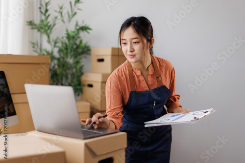 Bild auf Leinwand Asian female business owner managing online store operations, checking orders an
