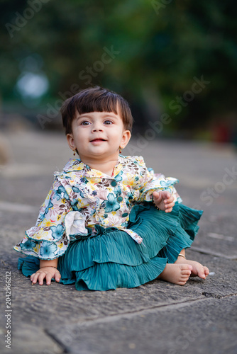 happy indian baby girl sitting on road at outdoor