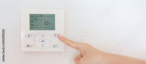 Quadro su tela operating and adjusting Air conditioner temperature by remote control in home