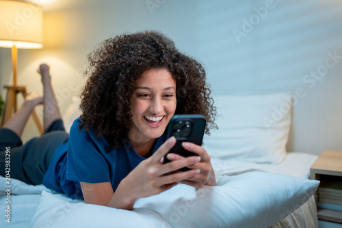 Foto Attractive Latina woman using mobile phone at night at home.