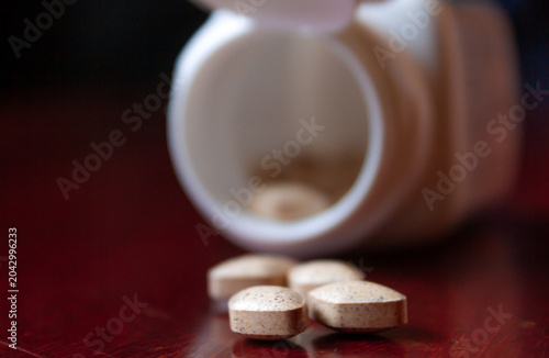 Pills spilling out of a bottle isolated on dark background, Vitamin for health