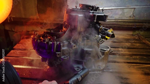 cleaning and washing with a steam cleaner of an old manual transmission from a front-wheel drive car for repair evening video shooting with red and purple lighting