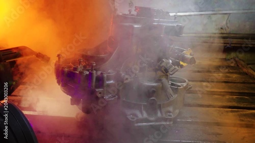 cleaning and washing with a steam cleaner of an old manual transmission from a front-wheel drive car for repair evening video shooting with red and purple lighting