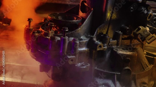 cleaning and washing with a steam cleaner of an old manual transmission from a front-wheel drive car for repair evening video shooting with red and purple lighting
