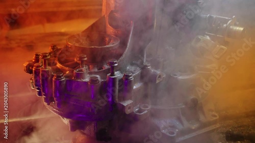 cleaning and washing with a steam cleaner of an old manual transmission from a front-wheel drive car for repair evening video shooting with red and purple lighting