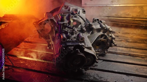 cleaning and washing with a steam cleaner of an old manual transmission from a front-wheel drive car for repair evening video shooting with red and purple lighting