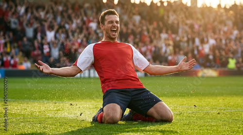 Soccer player celebrating goal with knee slide on field in stadium