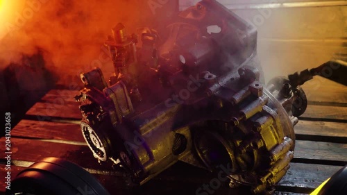 cleaning and washing with a steam cleaner of an old manual transmission from a front-wheel drive car for repair evening video shooting with red and purple lighting