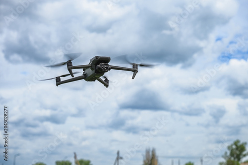 Modern quadcopter drone hovering in the air against dramatic cloudy sky. Unmanned aerial vehicle with camera used for photography, inspection, mapping and technology applications.