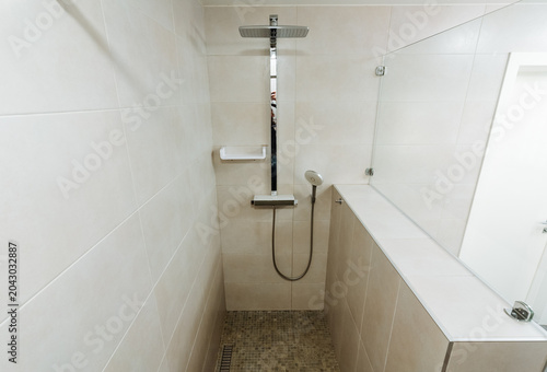 Tableau sur toile Modern tiled shower stall interior with wall-mounted showerhead and glass panel