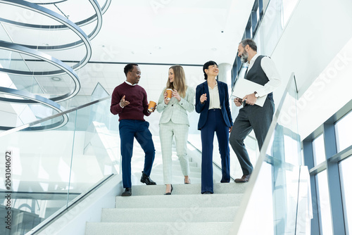 Tableau sur toile Diverse business team collaborating and communicating while walking downstairs i