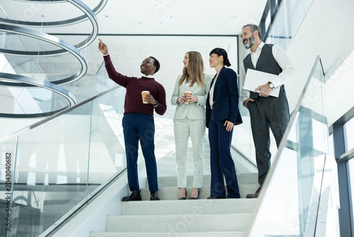 Cuadro en lienzo Group of multi-ethnic professionals standing on a modern office staircase, discu