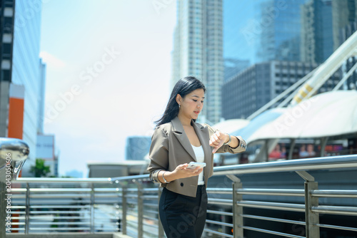 Businesswoman checks smartwatch while walking in modern city