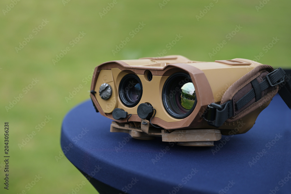 Fototapeta premium Night vision device, binoculars with thermal imaging capability, used by the military, police, and security services when searching for people, copy space