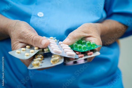 Fotografie Asian elderly woman holding pill drug in hand, strong healthy medical concept