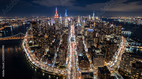 Aerial view of skyscrapers highway and buildings in Manhattan, New York City skyline, at night. 
